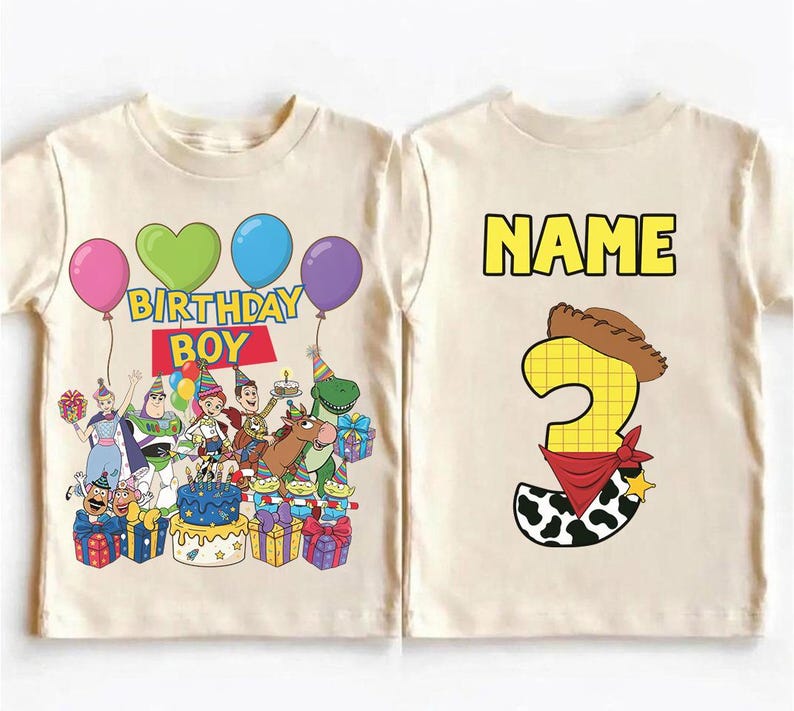 Op de afbeelding: Een cr&egrave;mekleurig T-shirt met een kleurrijke afbeelding van Toy Story-personages, ballonnen en de woorden "BIRTHDAY BOY". De achterkant van het shirt heeft het woord "NAME" boven een nummer 3 met een cowboyhoed en bandana.
