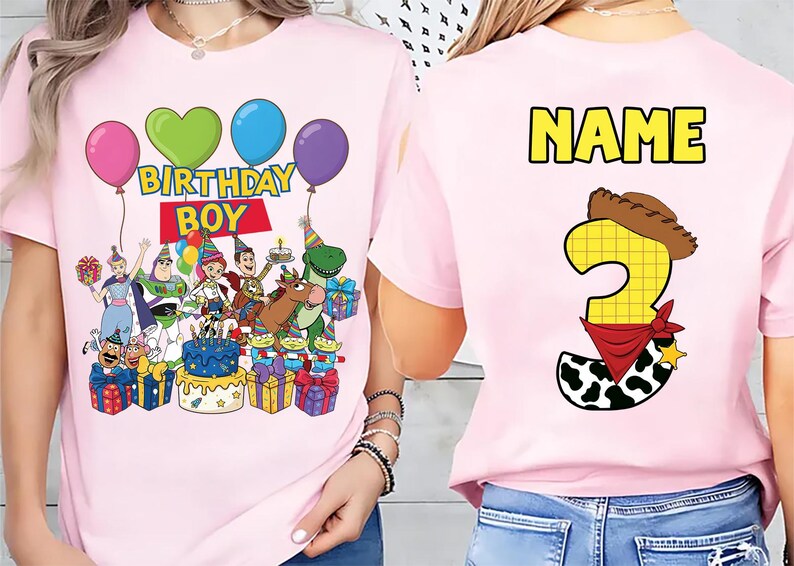 Op de afbeelding: Roze T-shirt met een Toy Story-ontwerp. De voorkant toont personages, ballonnen en "BIRTHDAY BOY". De achterkant heeft een nummer 3 met een cowboyhoed en bandana, en het woord "NAME" in geel.