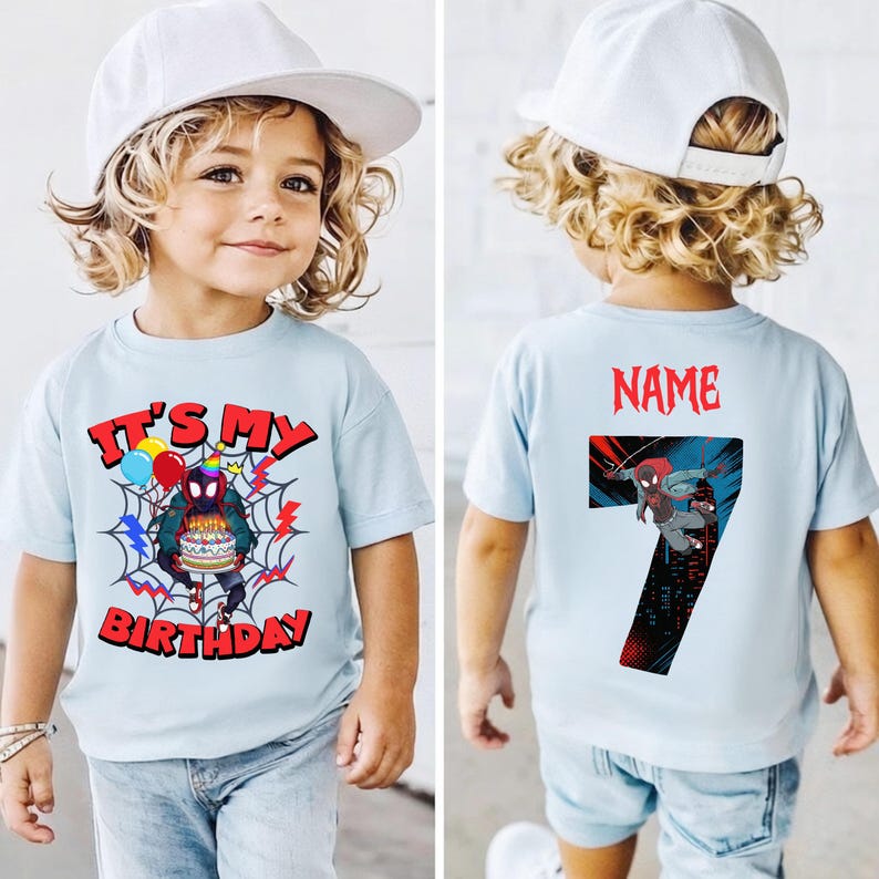 K&ouml;nnte beinhalten: Hellblaues T-Shirt mit einem Spider-Man-Motiv. Auf der Vorderseite steht in roter Schrift "IT'S MY BIRTHDAY". Auf der R&uuml;ckseite befindet sich die Zahl 7 und das Wort "NAME" in Rot. Das T-Shirt wird von einem Kind getragen.