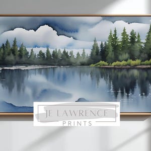 Puede incluir: Impresión artística de paisaje en acuarela que presenta una serena escena lacustre con reflejos de árboles y nubes. La obra de arte está enmarcada en un marco de madera de color dorado. El texto "JE LAWRENCE PRINTS" se muestra en la parte inferior de la imagen.