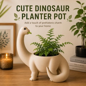 May include: A cream-coloured dinosaur-shaped planter pot with a long neck and a curled tail. The dinosaur has a small green leaf in its mouth and a green fern plant growing from the opening in its back. Text reads CUTE DINOSAUR PLANTER POT.