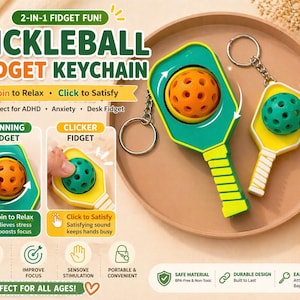 Puede incluir: Un llavero fidget de pickleball verde y amarillo con una pelota naranja y una pelota verde. El texto dice "2-IN-1 FIDGET FUN! PICKLEBALL FIDGET KEYCHAIN". El llavero está diseñado para girar y hacer clic, y es perfecto para el TDAH, la ansiedad y como fidget de escritorio.