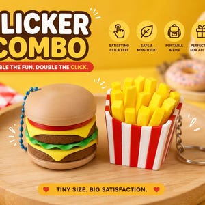 Könnte beinhalten: Ein neuartiges Schlüsselanhänger-Set mit einem Burger und Pommes Frites. Der Burger hat ein hellbraunes Brötchen, rote Tomate, grünen Salat und gelben Käse. Die Pommes sind gelb und in einem rot-weiß gestreiften Behälter. Der Text lautet "CLICKER COMBO".