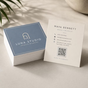 May include: A stack of square business cards with a blue front featuring a gold arch logo and the text LUNA STUDIO CREATIVE BRANDING. The cream-colored back displays the name MAYA BENNETT, contact details, a QR code, and the text SCAN TO CONNECT.