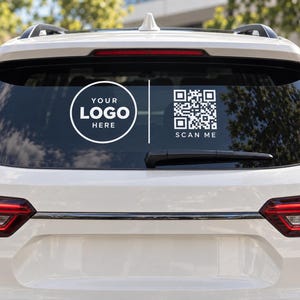Könnte beinhalten: Ein weißer Vinyl-Aufkleber auf der Heckscheibe eines weißen Fahrzeugs. Der Aufkleber zeigt links einen kreisförmigen Rahmen mit dem Text YOUR LOGO HERE und rechts einen quadratischen QR-Code mit dem Text SCAN ME darunter.