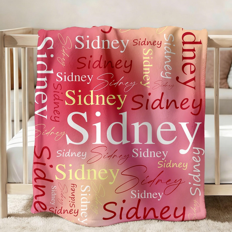 May include: A soft fleece blanket featuring a repeating pattern of the name Sidney in various fonts, sizes, and orientations. The background displays a gradient of colors transitioning from light yellow to pink and deep red.