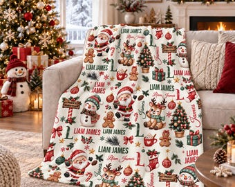 Könnte beinhalten: Eine cremefarbene Fleecedecke mit einem wiederkehrenden Weihnachtsmuster aus Weihnachtsmann, Rentieren, Schneemännern, Lebkuchenmännern, geschmückten Bäumen und Geschenken. Der Text Liam James ist in verschiedenen Schriftarten aufgedruckt.
