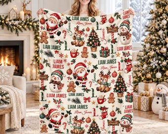 Könnte beinhalten: Eine cremefarbene Fleecedecke mit einem wiederkehrenden Weihnachtsmuster aus Weihnachtsmännern, Rentieren, Schneemännern, Lebkuchenmännern, geschmückten Bäumen und Geschenken. Der Text Liam James ist in Rot und Grün aufgedruckt.