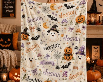 Könnte beinhalten: Eine cremefarbene Fleecedecke mit einem wiederkehrenden Halloween-Muster aus Geistern, Kürbissen, Fledermäusen, Spinnen, Pilzen und Schleifen. Der Name Josiah ist in verschiedenen Schriftarten und Farben über das Design verteilt.
