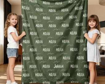Könnte beinhalten: Eine personalisierte olivgrüne Decke mit dem Namen "MIRAN" in einem sich wiederholenden Muster. Der Name "Johnson" ist ebenfalls in Schreibschrift enthalten. Diese individuelle Decke ist ein gemütliches und einzigartiges Geschenk.