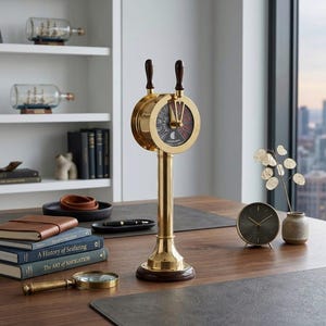 Può includere: Un telegrafo navale in ottone con base e manici in legno scuro. Il quadrante mostra indicatori direzionali. Altre decorazioni nautiche includono modelli di navi in bottiglia, libri sulla navigazione e una lente d'ingrandimento.
