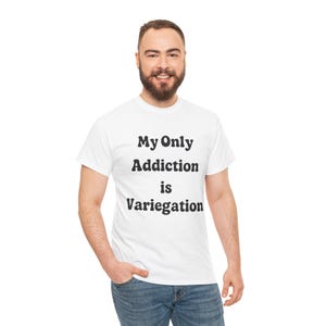 Può includere: T-shirt bianca con la scritta "My Only Addiction is Variegation" in nero. La maglietta è indossata da una persona con jeans blu. La persona sorride e guarda la fotocamera.