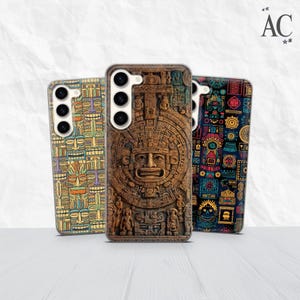 Può includere: Tre custodie per telefono con design unici. La custodia centrale presenta un'intagliatura dettagliata in stile azteco marrone. La custodia a sinistra ha un motivo ripetuto di maschere tribali colorate. La custodia a destra ha uno sfondo nero con un design geometrico colorato.