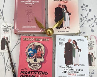 May include: Four hardcover books titled Draco Malfoy and the Mortifying Ordeal of Being in Love, a gold winged snitch, a wooden wand, and two bookmarks. The books feature illustrations of characters, a skull, and a rose. Text includes ISTHISSELFCARE.