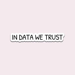 May include: A white sticker with the phrase "IN DATA WE TRUST" in black, handwritten-style font. The sticker has a white border and is set against a light pink background. The sticker is rectangular.