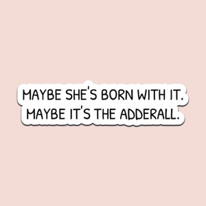 May include: A white sticker with black text that reads "MAYBE SHE'S BORN WITH IT. MAYBE IT'S THE ADDERALL." The sticker has a white border and is set against a light pink background.