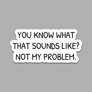 Könnte beinhalten: Ein weißer Aufkleber mit schwarzem Text, der lautet: "YOU KNOW WHAT THAT SOUNDS LIKE? NOT MY PROBLEM." Der Aufkleber hat einen abgerundeten Rand und ist vor einem grauen Hintergrund platziert. Der Text ist fett und ohne Serifen.