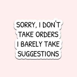 Op de afbeelding: Een witte sticker met zwarte tekst op een lichtroze achtergrond. De tekst luidt "SORRY, I DON'T TAKE ORDERS I BARELY TAKE SUGGESTIONS" in een vetgedrukte, handgeschreven lettertype. De sticker heeft een afgeronde rand.