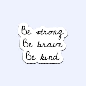 May include: A white sticker with black handwritten text that reads "Be strong, Be brave, Be kind." The sticker has a white border and is set against a light blue background.