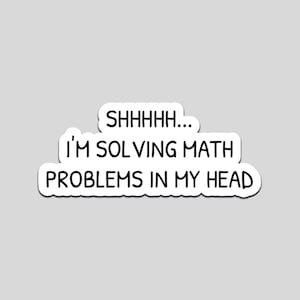 Pode incluir: Um autocolante branco com texto preto que diz "SHHHHH... I'M SOLVING MATH PROBLEMS IN MY HEAD". O autocolante tem uma borda branca e está sobre um fundo cinzento.