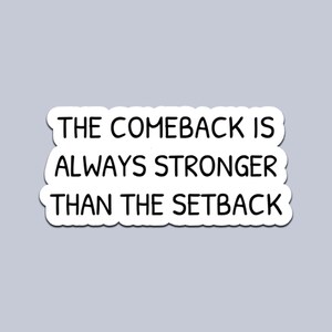 Könnte beinhalten: Ein weißer Aufkleber mit schwarzem Text, der lautet: "THE COMEBACK IS ALWAYS STRONGER THAN THE SETBACK". Der Aufkleber hat eine abgerundete, unregelmäßige Form auf hellgrauem Hintergrund.