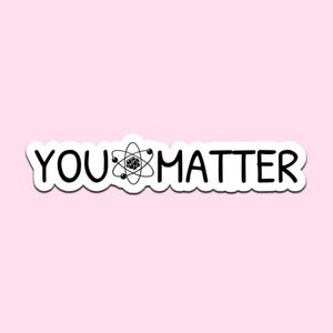 Peut inclure: Autocollant blanc avec texte noir « YOU MATTER ». Le mot « YOU » est suivi d'un graphique d'atome, puis du mot « MATTER ». L'autocollant est sur un fond rose clair.