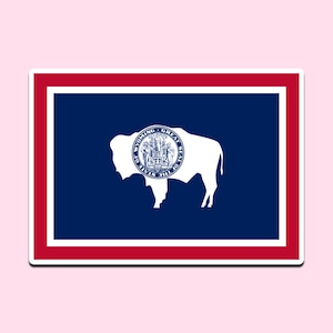 May include: A sticker featuring the Wyoming state flag. The flag has a blue background with a white bison in the center, and the state seal inside the bison. The flag is framed by a red border and a white border.