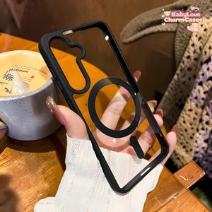 Puede incluir: Funda de teléfono transparente con marco negro y diseño circular negro. La funda tiene una parte trasera transparente y un borde negro. El texto "BabyLove CharmCases" es visible en la esquina superior derecha.
