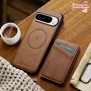 Puede incluir: Funda de teléfono de cuero marrón con un símbolo de carga inalámbrica y un tarjetero a juego. La funda tiene un borde negro y el tarjetero tiene una tarjeta con el texto "Fierre Shann". La funda y el tarjetero están sobre una superficie de madera.
