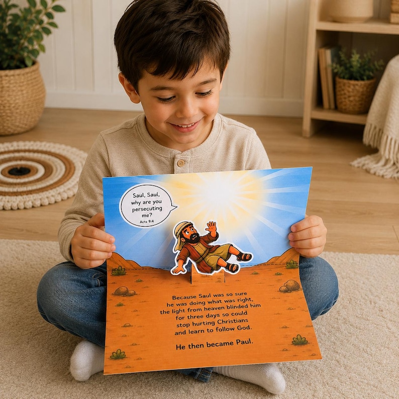 May include: A young child is smiling while holding open a colorful pop-up book. The book features an illustration of a biblical scene with text that reads "Saul, Saul, why are you persecuting me?" and "He then became Paul."