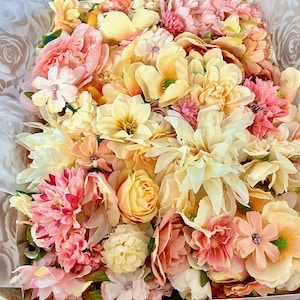 Puede incluir: Un arreglo denso de flores artificiales en tonos crema, amarillo p&aacute;lido, melocot&oacute;n y rosa suave. La colecci&oacute;n incluye varias formas y tama&ntilde;os de p&eacute;talos, con flores en capas, capullos redondeados y centros peque&ntilde;os, todos muy juntos.