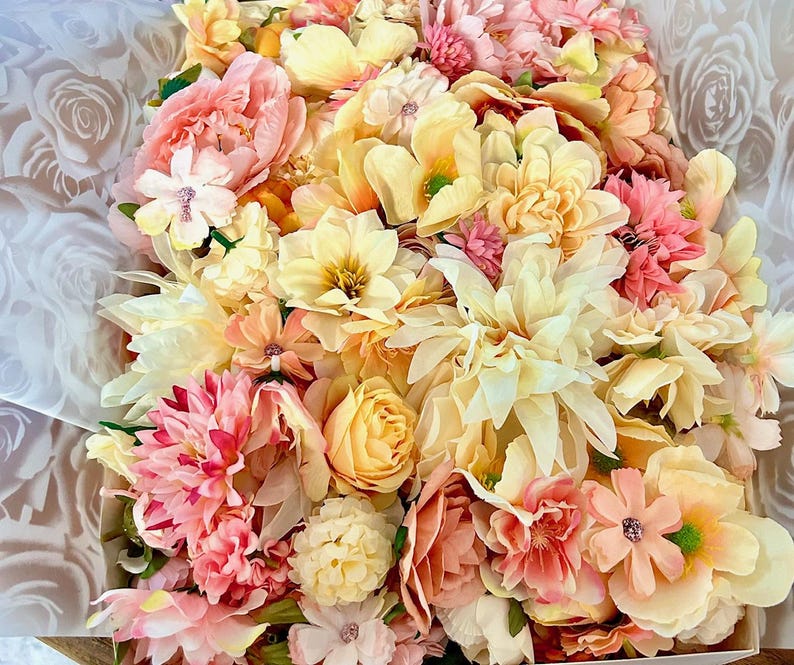 Puede incluir: Un arreglo denso de flores artificiales en tonos crema, amarillo p&aacute;lido, melocot&oacute;n y rosa suave. La colecci&oacute;n incluye varias formas y tama&ntilde;os de p&eacute;talos, con flores en capas, capullos redondeados y centros peque&ntilde;os, todos muy juntos.