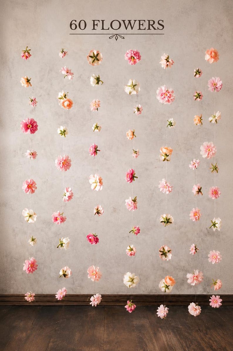 Puede incluir: Un colgante decorativo de pared con 60 flores dispuestas en hilos verticales. Las flores artificiales presentan diversos tonos de rosa, melocot&oacute;n y blanco, suspendidas mediante hilos finos y transparentes. El texto 60 FLOWERS aparece arriba.
