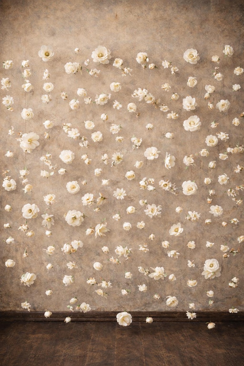 Puede incluir: Un tel&oacute;n de fondo con una superficie marr&oacute;n texturizada y moteada, adornado con numerosas flores artificiales peque&ntilde;as de color crema dispersas por toda el &aacute;rea, creando un denso patr&oacute;n floral que cubre la pared de arriba a abajo.