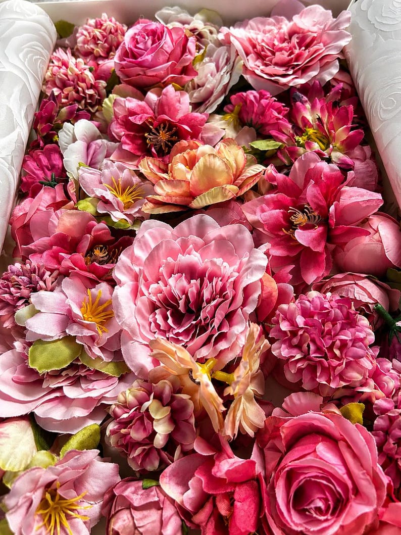 Puede incluir: Una colecci&oacute;n de flores artificiales en varios tonos de rosa, magenta y melocot&oacute;n. El arreglo presenta m&uacute;ltiples tipos de flores, incluyendo rosas, peon&iacute;as y flores m&aacute;s peque&ntilde;as con centros amarillos, todas agrupadas estrechamente.