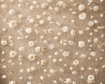 Puede incluir: Una guirnalda floral de color marfil natural DIY con numerosas flores de tela pequeñas de color crema suspendidas en hilos verticales finos contra una pared texturizada de color marrón moteado con una base de suelo de madera oscura.