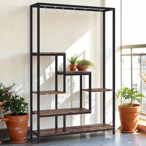 Puede incluir: Un estante para plantas de metal negro con múltiples estantes y una barra superior con ganchos. Los estantes tienen un acabado de vetas de madera, y varias plantas en macetas se exhiben. El estante está diseñado para uso en interiores o exteriores.