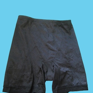 May include: Black compression shorts with a textured pattern. The shorts have a high waist and extend to mid-thigh. The fabric appears to be a smooth, stretchy material. The shorts are designed for shapewear.