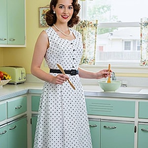 May include: A sleeveless white dress featuring a black polka dot pattern, a square neckline, and a row of black buttons down the front bodice. The dress is cinched at the waist with a solid black belt and has a full, knee-length skirt silhouette.