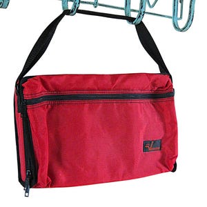 May include: A red messenger bag with a black zipper and strap hangs from a decorative, turquoise-colored metal hook. The bag has a rectangular shape and a small logo on the lower right corner.