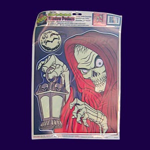 May include: Glow-in-the-Dark Window Peekers Halloween decoration. Features a skeletal figure in a red hooded cloak holding a lantern. The design includes a full moon and bats. The packaging is visible.