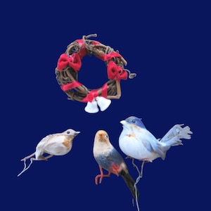 May include: A small, woven wreath with red bows and white accents, accompanied by three decorative birds. The birds feature white, blue, and orange coloring, with delicate details. The background is a solid, dark blue.