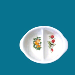 May include: A white ceramic divided dish with a floral design. One side features oranges and the other side features strawberries.