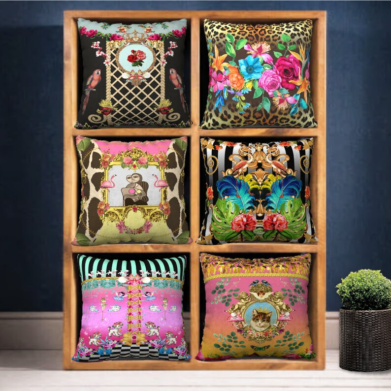 May include: Six decorative throw pillows with various colorful patterns and designs. The pillows are displayed on a wooden shelf with a dark blue background.