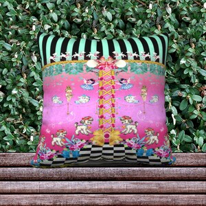 May include: A pink and green throw pillow with a whimsical design featuring dancing dolls, dogs, and a checkered pattern.