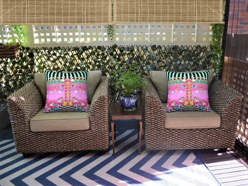 May include: Two wicker chairs with beige cushions and pink and black patterned throw pillows. The chairs are on a black and white chevron patterned rug.