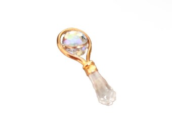 Op de afbeelding: Een goudkleurige, met draad omwikkelde hanger met een bolvormige iriserende kraal in een cirkelvormig draadframe, verbonden met een helder, getextureerd, langwerpig glazen onderdeel dat taps toeloopt naar de onderkant van het sieraad.
