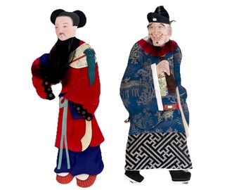 Op de afbeelding: Twee schaduwpoppen met gedetailleerde traditionele kleding. De linkerpop draagt een rood gewaad met blauwe accenten en een zwarte baard. De rechterpop draagt een blauw gewaad met patronen, een rode kraag en een zwarte hoed met ingewikkelde details.