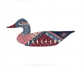 Op de afbeelding: Een eendvormige sleutelhouder voor aan de muur met een patchworkontwerp in verschillende patronen in tinten blauw, roze en donkerrood. De eend heeft een rode snavel en zes witte haken aan de onderkant voor het ophangen van sleutels of items.