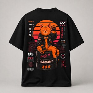 May include: Black t-shirt featuring a cartoon orange cat wearing a black jacket, sitting on tires, and raising a paw. The design includes Japanese text, a rising sun, and a race car. The text "lucky" and "Speed is Fortune" are also present.